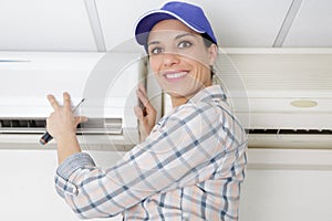 Happy woman fixing air conditioner at home