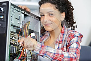 happy woman fixing computer at desk at work
