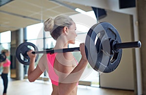 Happy woman flexing muscles with barbell in gym