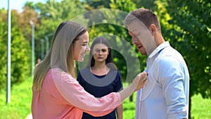 Happy woman flirting with man, jealous brunette friend on background, betrayal