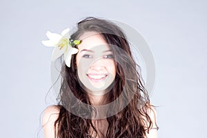 Happy woman with flower in curly hair with smile with teeth. SPA treatment.