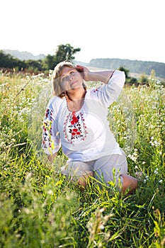 Happy woman with flower relaxes in the grass with a flower.