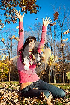 Happy woman with foliage in autumn