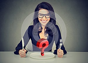 Happy woman with fork and knife sitting at table with empty plate