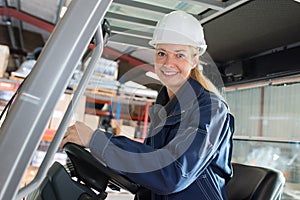 happy woman forklift truck driver in industrial area
