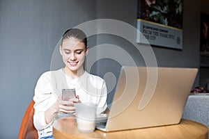 Cheerful female marketer chatting on mobile phone, sitting with notebook in bar