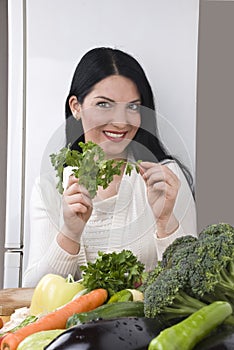 Happy woman with fresh parsley and vegetables