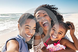 Happy woman friends with child taking selfie at seaside