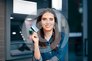 Happy Woman in Front of ATM Machine Holding Card photo