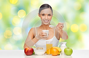 Happy woman with fruits, cereals eating yogurt