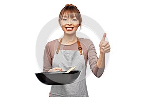 happy woman with frying pan showing thumbs up