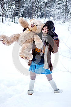 Happy woman in fur coat and ushanka with bear on white snow winter background photo