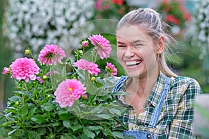 Happy  woman gardener choosing flower pot with anthuriums in garden center