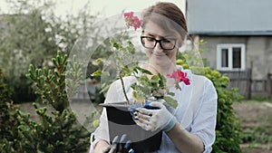 Happy woman gardener holding flowers smiling at camera while working in her garden in spring