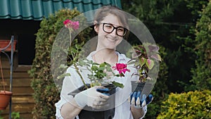 Happy woman gardener holding flowers smiling at camera while working in her garden in spring