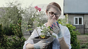 Happy woman gardener holding flowers smiling at camera while working in her garden in spring