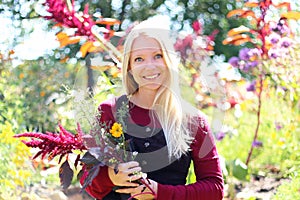 A Happy Woman Gardener is Smiling as She Holds Flowers in her Cottage Garden