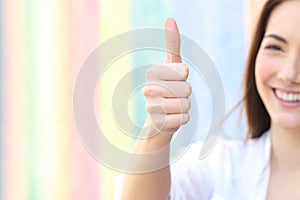 Happy woman gesturing thumbs up in a colorful street