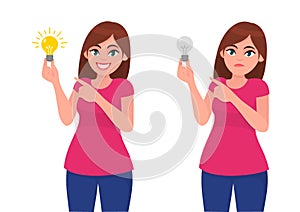 Happy woman/girl holding bright bulb and pointing index finger. Unhappy woman/girl holding dull bulb and pointing to it. Idea.