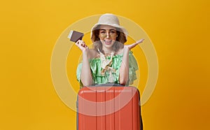 Happy woman girl with suitcase and passport on yellow background. concept of travel