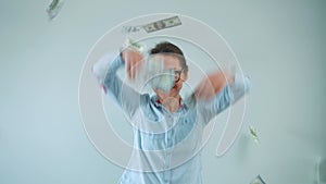 Happy woman with glasses making money rain from dollar bills