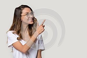 Happy woman in glasses pointing finger at copy space