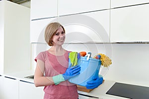 Happy woman in gloves holding cleaning bucket with cloth and household