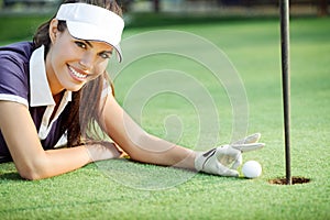 Happy woman golf pushing golf ball into the hole