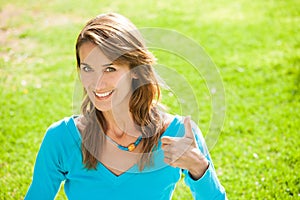 Happy woman in a green garden thumb up