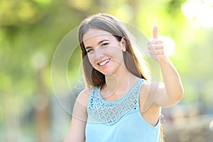 Happy woman on green gesturing thumbs up in a park