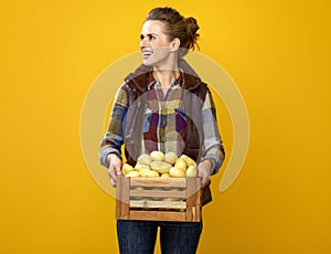 Happy woman grower with box of potatoes looking at copy space