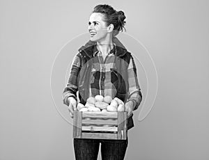 Happy woman grower with box of potatoes looking at copy space