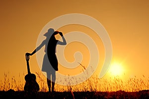 Happy woman and guitar with sunset silhouette