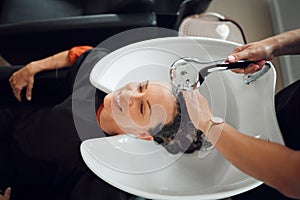 Happy woman, hairdresser and washing hair at luxury salon with water, tap and basin from above. Female customer or