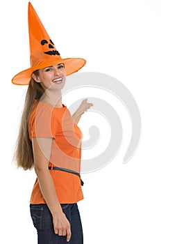 Happy woman in Halloween hat pointing on back