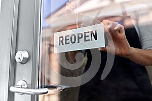 happy woman hanging reopen banner on door glass