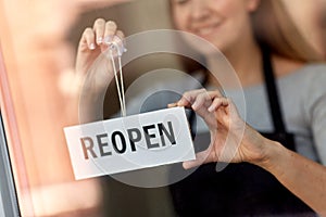 happy woman hanging reopen banner on door glass