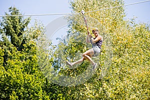 Happy Woman Hanging On Zip Line In Forest