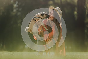 Happy woman in hat is kissing her puppy