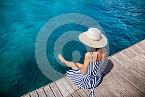 Happy woman in hat relaxing on sea pier in Sardinia island, Italy