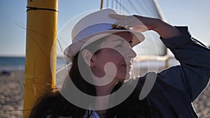 Happy woman in a hat stands on the beach and looks around