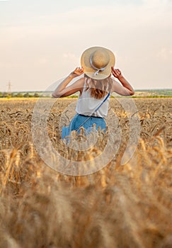 Happy woman with hat in summer field golden wheat, beautiful summer season. Girl enjoying life in colorful field ripe
