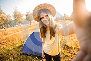Happy woman in hat take selfie with camera after wake up in tent in autumn morning