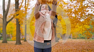 Happy woman having fun with leaves in autumn park