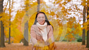 Happy woman having fun with leaves in autumn park