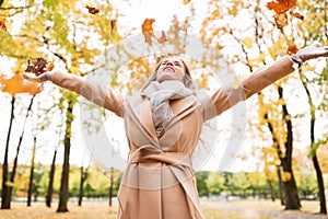 Happy woman having fun with leaves in autumn park