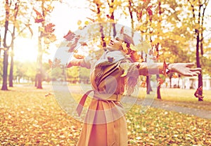 Happy woman having fun with leaves in autumn park