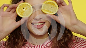 Happy woman having fun with lemon halves in studio. Fashion model face smiling