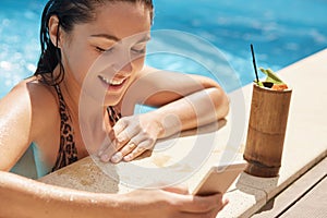 Happy woman having fun at luxury resort, female drinking fresh cocktail while being near edge of pool and checking social networks