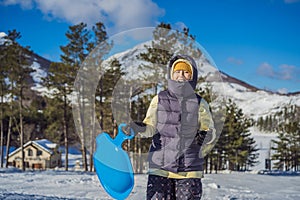 Happy woman having fun during rolling down the mountain slope on sled. Winter sports with snow. People riding a sledge